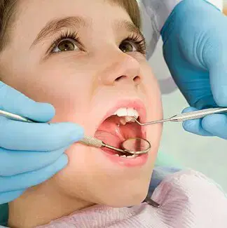 Children’s Dental Examination Child having their teeth examined with a dental mirror and probe